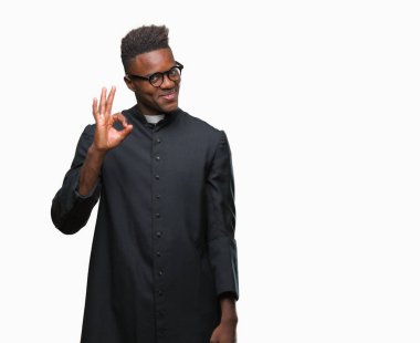 Gülümseyen izole arka plan üzerinde genç Afro-Amerikan rahip adam el ve parmaklar ok işaretiyle yapıyor olumlu. Başarılı ifade.