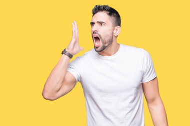 Bağırarak ve ağzı üzerinde el ile yan için çığlık izole arka plan üzerinde rahat beyaz t-shirt giyen genç adam. İletişim kavramı.