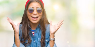 Genç güzel Arap kadın üzerinde güneş gözlüğü takıyor deli kutluyor arka plan izole ve silah ile başarı için yükseltilmiş ve açık gözleri heyecanlı çığlık hayrete düşürdü. Kazanan kavramı