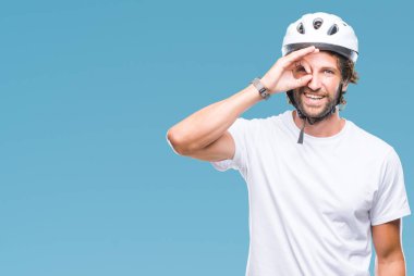 Yakışıklı İspanyol bisikletçi adamın gülümseyen, parmakları ile mutlu yüz üzerinden seyir göz el ile ok jest yapıyor izole arka plan üzerinde güvenlik kask giydiğini.
