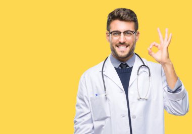 Genç yakışıklı adam izole arka plan el ve parmaklar ok işaretiyle yapıyor olumlu gülümseyen üzerinde doktor. Başarılı ifade.