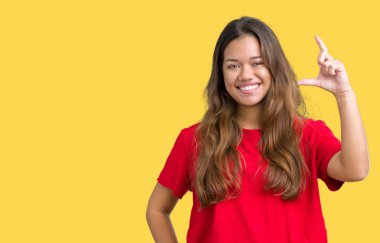 İzole arka plan gülümseyen ve süre seyir ve kamera boyutu işaret parmaklarıyla yapıyor el ile kendinden emin eller üzerinde kırmızı t-shirt giyen genç güzel esmer kadın. Ölçü kavramı.