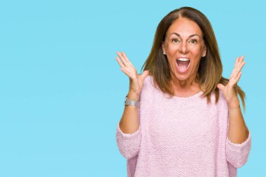 Üzerinde kış kazak giyen güzel orta yaş yetişkin kadın deli kutluyor arka plan izole ve başarı için kaldırdı kollarını açarak hayrete ve heyecanlı çığlık gözleri açık. Kazanan kavramı