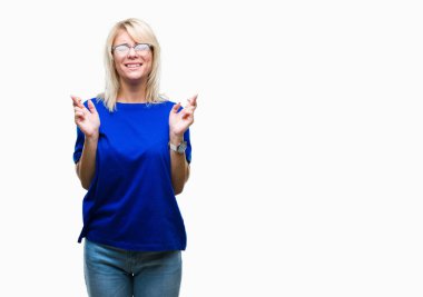 Umut ve gözleri kapalı geçiş parmaklarıyla gülümseyen izole arka plan üzerinde gözlük takan genç güzel sarışın kadın. Şans ve batıl kavramı.