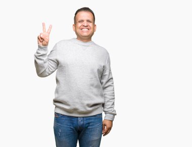 Gösterilen arka plan üzerinde spor kazak giyen orta yaş Arap adam izole ve parmakları ile işaret kendinden emin ve mutlu gülümseyerek ise ikinci.