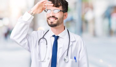 Genç çok mutlu ve gülümseyen uzakta el ile üzerine kafa seyir izole arka plan üzerinde hastane ceket giyen adam doktor. Arama kavramı.