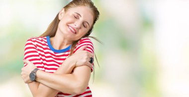 Orta yaş Olgun kadın rahat t-shirt üzerinde izole giyen emin gülümseyen Hugging kendini mutlu ve olumlu, arka plan. Kendi aşk ve öz bakım
