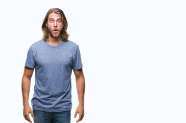 Korkuyor ve şok sürpriz ifade ile izole arka plan üzerinde uzun saçlı yakışıklı delikanlı korku ve yüz heyecanlı.