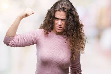 Güzel esmer kıvırcık saçlı Genç kız öfkeli ve sinirli sinirli ve öfke ile bağırarak süre öfkeli yumruk yükselterek izole arka plan üzerinde pembe kazak giyiyor. Öfke ve agresif kavramı.