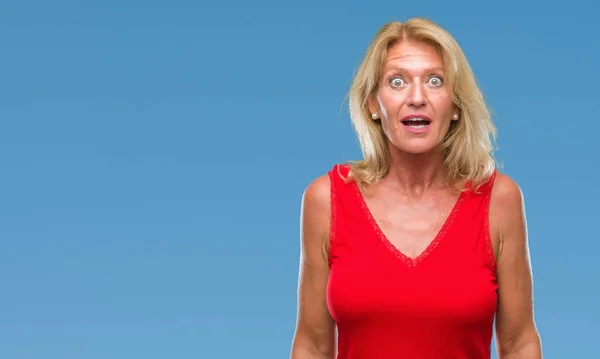 Middle age blonde woman over isolated background afraid and shocked with surprise expression, fear and excited face.