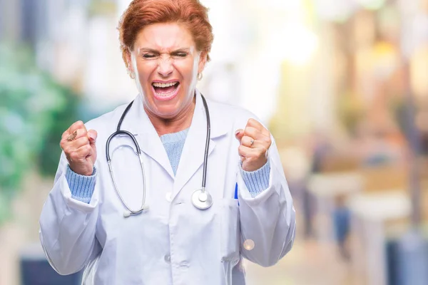 先輩の白人医師女性の腕の成功のために興奮して孤立した背景に医療制服を着て祝う勝利笑顔に発生します 勝者の概念 — ストック写真