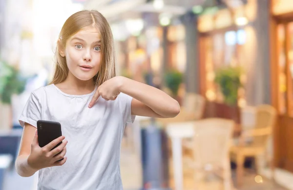 年轻美丽的女孩发送消息短信使用 Smarpthone 在孤立的背景和惊讶的脸指向自己的手指 — 图库照片