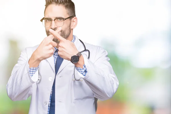 Handsome young doctor man over isolated background Rejection expression crossing fingers doing negative sign