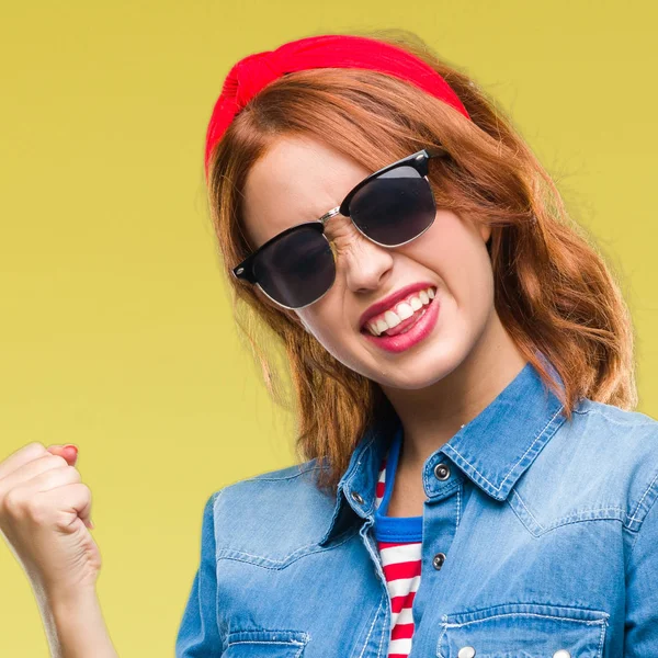 Gülümseyen ve başarı için çığlık genç güzel kadın izole arka plan çok mutlu ve heyecanlı kaldırdı, silah ile kazanan jest yapıyor güneş gözlüğü takıyor. Kutlama kavramı.