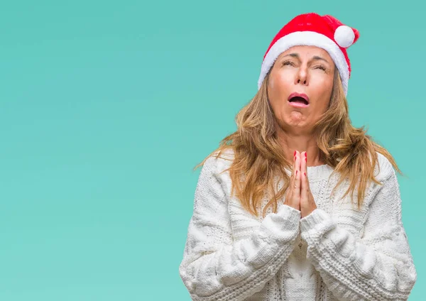 懇願するような非常に感情的なおよび心配の顔希望表現とともに手で祈って分離の背景にクリスマスの帽子を着て中年年配のヒスパニック系女性 赦しを乞います 宗教概念 — ストック写真