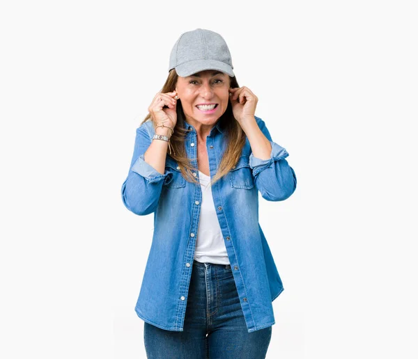 騒々しい音楽のノイズの腹式指で耳を覆う孤立した背景にスポーツ キャップを着て美しい中年女性 聴覚障害者の概念 — ストック写真