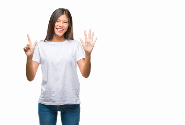 Молодая азиатка на изолированном фоне показывает и показывает пальцами номер семь, улыбаясь уверенно и счастливо
.