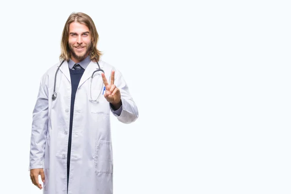 年轻英俊的医生男子与长发在孤立的背景微笑着看着相机显示手指做胜利标志 第二个 — 图库照片