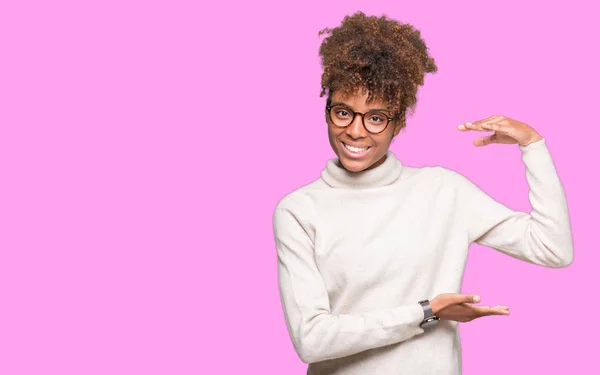 美丽的年轻非洲裔美国妇女戴眼镜在孤立的背景示意与手显示大和大尺寸的标志 措施符号 看着镜头微笑 测量概念 — 图库照片