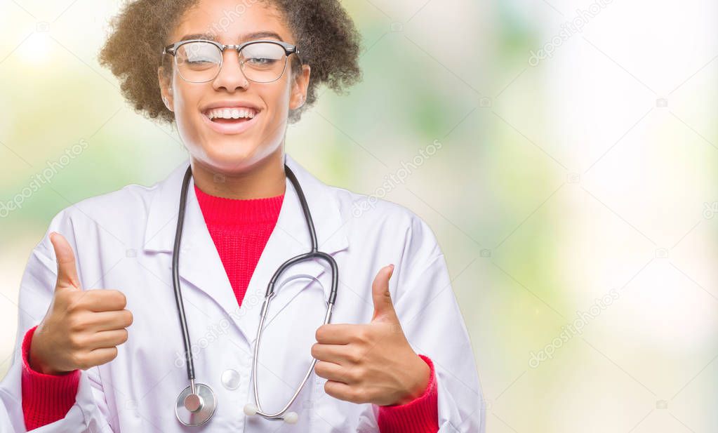 Young afro american doctor woman over isolated background success sign doing positive gesture with hand, thumbs up smiling and happy. Looking at the camera with cheerful expression, winner gesture.