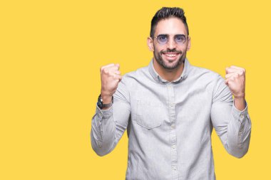 Yakışıklı delikanlı izole arka plan kutlama üzerinde güneş gözlüğü takıyor şaşırttı ve başarı için kaldırdı kollarını açarak hayret ve gözleri açık. Kazanan kavramı.