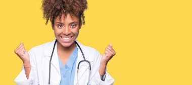 İzole arka plan kutlama üzerinde genç Afro-Amerikan doktor kadın şaşırttı ve silah ile başarı için yükseltilmiş ve açık gözler hayrete düşürdü. Kazanan kavramı.