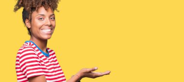 İzole arka plan güzel genç Afro-Amerikan kadın el ve reklam mutlu ve kendinden emin gülümseyen sunulması avuç, yanında işaret