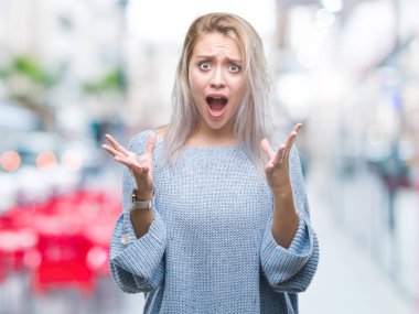 Üzerinde kış kazak giyen genç sarışın kadın arka plan deli izole ve deli bağırarak ve agresif ifade ve silah kaldırdı bağırıyor. Hayal kırıklığı kavramı.