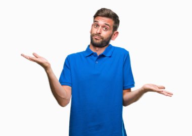 İzole arka plan clueless ve şaşkın bir ifadeyle kollar ve eller kaldırdı genç yakışıklı adam. Şüphe kavramı.