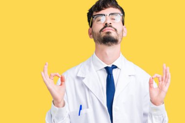 İzole arka plan üzerinde beyaz önlük giyen genç profesyonel bilim adam rahatla ve gülümseyen gözlerle kapalı parmak jestle meditasyon yapıyor. Yoga kavramı.