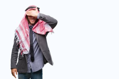 Genç yakışıklı Arap adam uzun saçlı gülümsüyor ve gözleri için sürpriz kapsayan yüz el ile gülüyor izole arka plan üzerinde keffiyeh giyiyor. Kör kavramı.