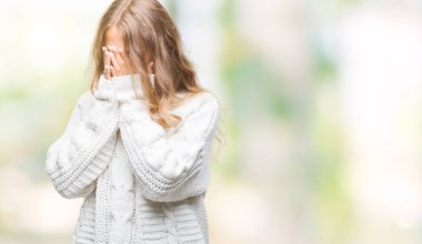 Üzgün ifade yüz eller ile ağlayarak süre kapsayan ile izole arka plan üzerinde kış kazak giyen güzel genç sarışın kadın. Depresyon kavramı.