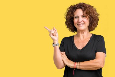 Kameraya bakarak yan el ve parmak ile işaret eden güzel orta ager üst düzey kadın yüzünde kocaman bir gülümseme ile izole arka plan.