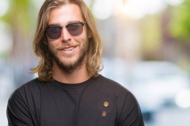 Mutlu yüz ile gülümseyerek kameraya seyir silah geçti arka plan üzerinde güneş gözlüğü takmış uzun saçlı yakışıklı delikanlı izole. Olumlu bir kişi.