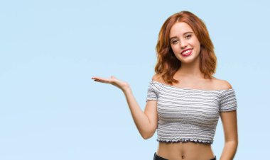 Neşeli sunulması ve kameraya bakarak avucunun ile işaret gülümseyen izole arka plan üzerinde genç güzel kadın.