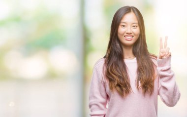 Genç Asyalı kadın mutlu yüz zafer işareti yaparken kameraya göz kırpıyor ile gülümseyen izole arka plan üzerinde. İki numaralı.