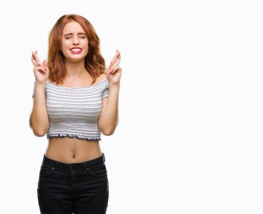 Umut ve gözleri kapalı geçiş parmaklarıyla gülümseyen izole arka plan üzerinde genç güzel kadın. Şans ve batıl kavramı.