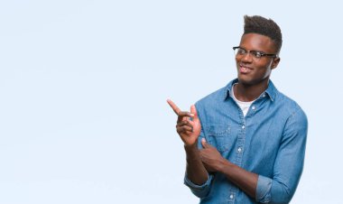Kameraya bakarak yan el ve parmak ile işaret eden genç Afro-Amerikan adam yüzünde kocaman bir gülümseme ile izole arka plan üzerinde.