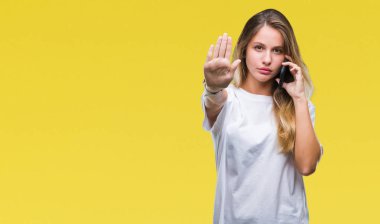 Genç güzel sarışın kadın ile izole arka plan üzerinde Smartphone kullanarak arama açık el dur işareti ile ciddi ve kendine güvenen ifade, savunma hareketi yapıyor