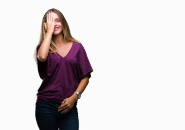 Genç güzel sarışın zarif kadın el yüz ve sürpriz duygu kendinden emin gülümseme ile tek gözüyle kapsayan izole arka plan.