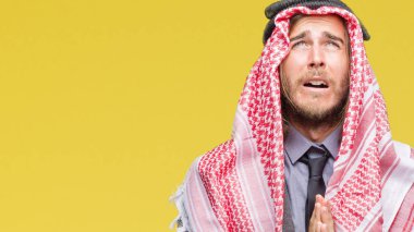 Genç yakışıklı Arap adam uzun saçlı keffiyeh yalvarıyor ve umut ifade yüzünde çok duygusal ve endişe ile birlikte elleriyle dua izole arka plan üzerinde giyiyor. Bağışlanmak. Din kavramı.