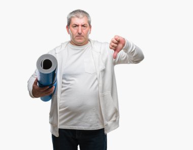 Kızgın yüz, eksi işareti aşağı antipati başparmak ile gösterilen, ret kavramı ile izole arka plan üzerinde yoga mat holding üst düzey yakışıklı