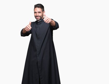 Genç Hıristiyan rahip üzerinde izole arka plan başarı için mutlu ve onaylama gülümseyerek el, başparmak ile olumlu hareketi yapıyor. Kamera, kazanan jest arıyorsunuz.