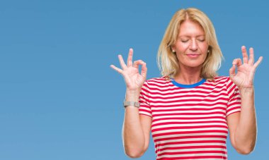 Orta yaş sarışın kadın izole arka plan üzerinde dinlenmek ve gülümseyen gözlerle parmak ile meditasyon jest yapıyor kapalı. Yoga kavramı.