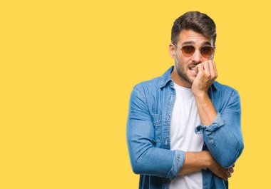 Genç yakışıklı adam stresli ve gergin ile izole arka plan üzerinde güneş gözlüğü takıyor tırnak ısırma dudaklarından eller. Anksiyete sorunu.