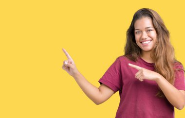 Genç güzel esmer kadın gülümseyerek ve iki elleri ve parmakları ile tarafına işaret kamera bakarak izole arka plan üzerinde.