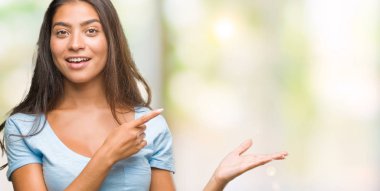 Genç güzel Arap kadın üzerinden hayran ve el ile sunulması ve parmak ile işaret ederken kameraya gülümseyen izole arka plan.