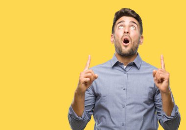 Yakışıklı delikanlı izole arka plan üzerinden hayran ve yukarıya bakıp parmakları ile işaret şaşırttı ve silah kaldırdı.