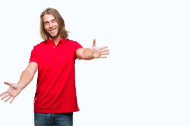 Sarılmak için kollarını açarak gülümseyerek kameraya bakarak izole arka plan üzerinde uzun saçlı Genç yakışıklı adam. Neşeli ifade kucaklayan mutluluk.