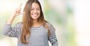 Giyen genç güzel esmer kadın kazak izole arka plan gülümseyen ve süre seyir ve kamera boyutu işaret parmaklarıyla yapıyor el ile kendinden emin eller üzerinde çizgili. Ölçü kavramı.